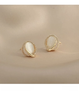 Macro shot of oval cat eye stone earrings with zircon halo on champagne velvet
