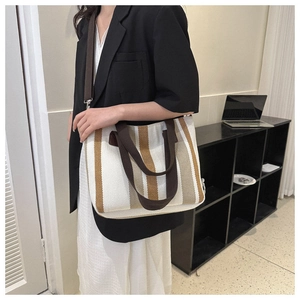 Vertical striped canvas tote bag shown as cross-body style with adjustable brown shoulder strap