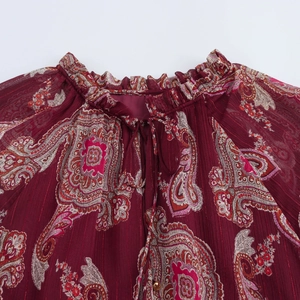 Détail de l'encolure à volants avec cordon sur la blouse paisley rouge foncé