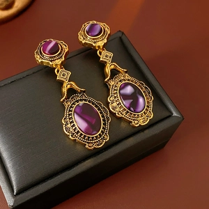 Detail of vintage gold earrings with purple oval gemstones on a black display box
