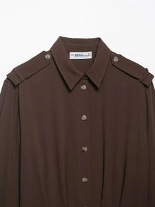 Detailed view of dark brown shirt featuring epaulettes and refined collar texture