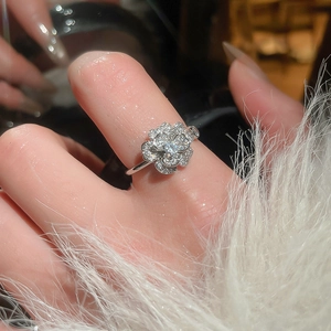 Close-up of silver flower ring with pave-set zircon petals worn on a finger