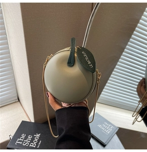 Detail of apple-shaped crossbody bag in olive green with gold leaf charm and chain