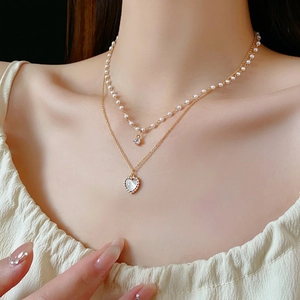 Elegant double layer heart necklace with white pearls and gold chain on model neck