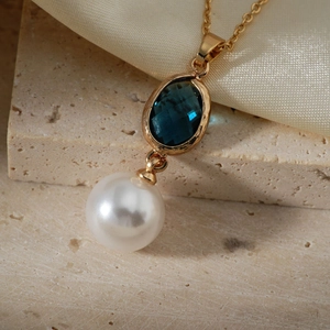 Collier en or luxueux avec une pierre ovale bleue facettée et une perle blanche ronde