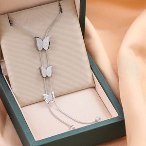 Collier à trois papillons argenté sur écrin vert avec fond en velours champagne