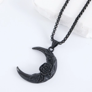 Close-up of black moon and rose pendant necklace with detailed engravings on white stone