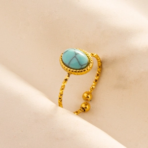 Close-up of golden adjustable ring featuring a turquoise stone and textured metal band