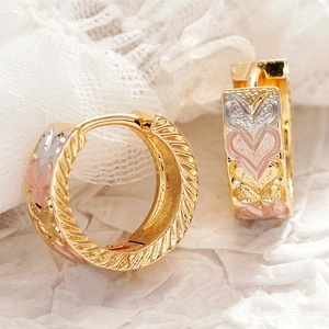 Detail van gouden huggie-oorbellen met kleurrijke emaille hartjes en randen