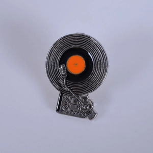 Macro view of a retro vinyl record player enamel pin in silver and orange tones