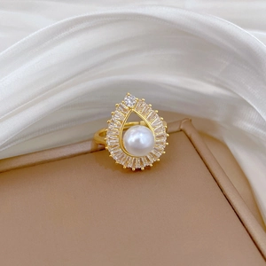 Macro shot of gold teardrop necklace featuring a central white pearl and zircon accents