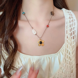 Détail du collier bohème avec pendentif fleur dorée et perles en bois colorées sur un mannequin