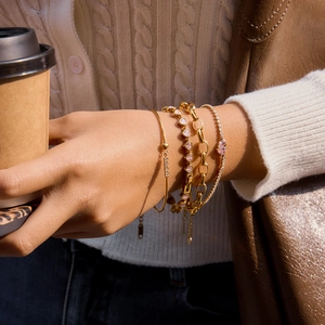 Detailed view of layered 18K gold plated heart bracelets with pink zircons on wrist