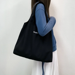 Vue latérale du grand sac cabas noir en toile avec texte Simplicity sur un mannequin