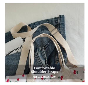Detailed view of the wide woven strap and reinforced stitching on the canvas tote bag