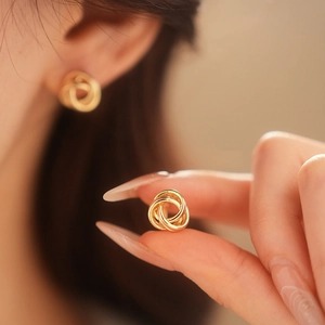 Vue détaillée de boucles d'oreilles nœuds dorés montrant la texture métallique de qualité