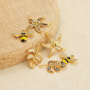 DIY jewelry charm set with bee, starfish and leaf pendants on rustic wood background