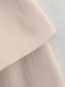 Close-up of beige twill fabric texture showing detailed weaving on sleeveless dress