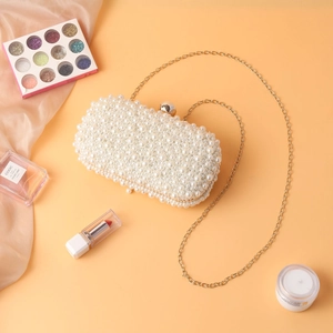 Elegant handmade pearl evening bag with gold chain strap on a warm silk background
