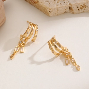 Detailed macro of gold-plated drop earrings featuring three-tier rings and zircon stones