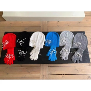 Flat lay of knit beanies and gloves set in multiple colors with bow tie details