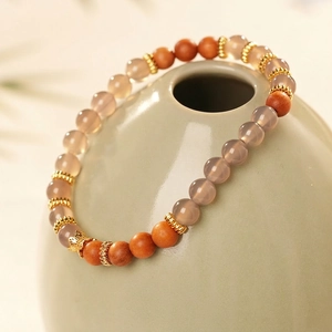 Bracelet rétro en bois de santal et agate grise avec accents dorés sur vase en céramique