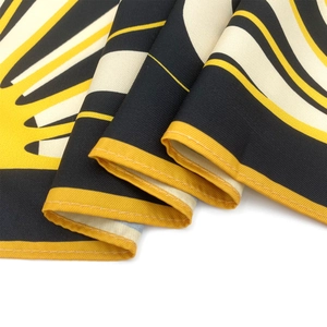 Macro detail of silk scarf showing yellow black white geometric pattern and twill texture