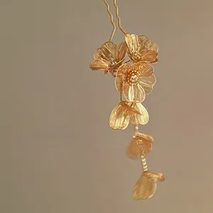 Détail d'épingle à cheveux fleur dorée avec strass et pendentifs en forme de feuille
