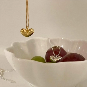 Elegant 925 sterling silver heart necklaces in gold and silver finish on a white bowl