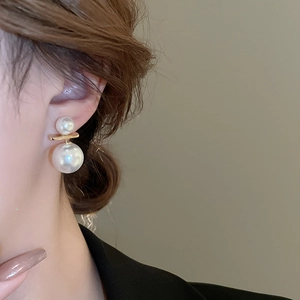 Detail of elegant gold bar earrings with double pearls on a model ear for fashion style