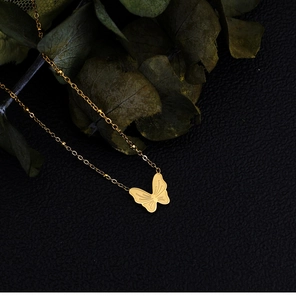 Nahaufnahme eines goldenen Schmetterlingsanhängers mit gestreifter Kette auf Perlenband