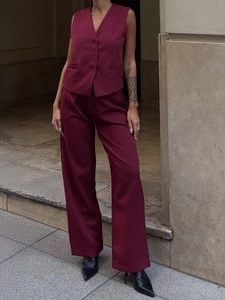 Detail of burgundy vest and wide-leg trousers set with button closure and elegant drape