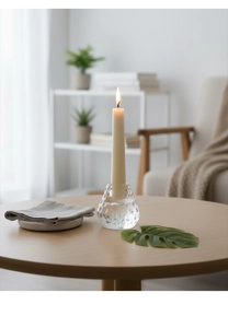 Detailansicht eines Kerzenhalters aus Glas mit brennender langer beiger Kerze