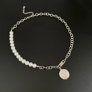 Detail of unique necklace with half pearls and half metal chain with coin pendant