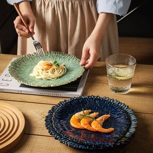 Top view of ceramic pasta plates in blue and green with textured edges on wood table