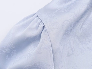 Detaillierte Makroansicht des hellblauen Jacquard-Stoffs mit elegantem Blumenmuster-Struktur