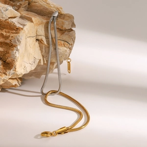 Two-tone silver and gold stainless steel snake chain bracelet on natural stone
