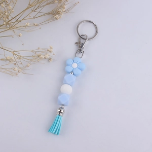 Detail of blue and white silicone bead keychain with floral charm and soft tassel