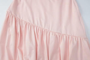 Detail view of pink ruffled hem with diagonal seam stitching on a slim-fit dress