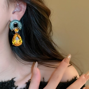 Close-up of vintage teardrop earrings with amber crystals on a model's ear