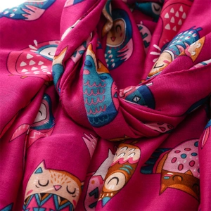 Close-up of pink linen-feel scarf featuring a colorful cartoon owl pattern and soft texture