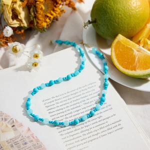 Classic 18K gold stainless steel necklace with blue turquoise beads on a book