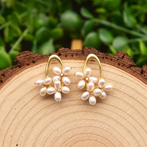 Elegant 925 silver needle pearl flower stud earrings with gold base on a rustic wood background