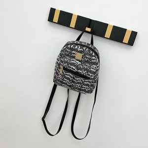 Detail of mini backpack featuring black and white woven texture and gold zipper hardware
