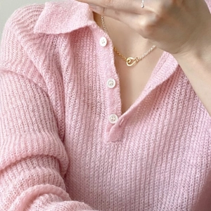 Close-up of pink knit top paired with gold and silver heart toggle pendant necklace