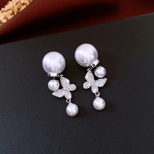 Vue macro de boucles d'oreilles papillon en perles et strass sur fond de cuir noir