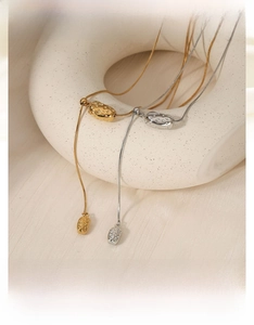 Close-up of gold and silver irregular geometric necklaces on a white ceramic display
