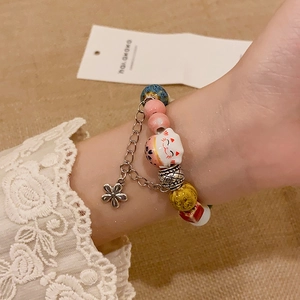 Close-up of a beaded cat bracelet with ceramic charms and metallic flower detail