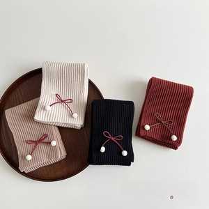 Detailed view of knitted winter scarves with ribbon bows and soft pom-poms in four colors