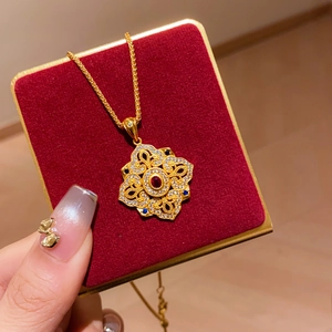 Macro shot of vintage mandala gold cross pendant with red and blue gemstones